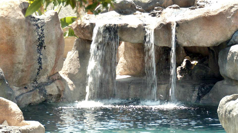 Concrete rock grotto with dual waterfalls flanking a cave opening