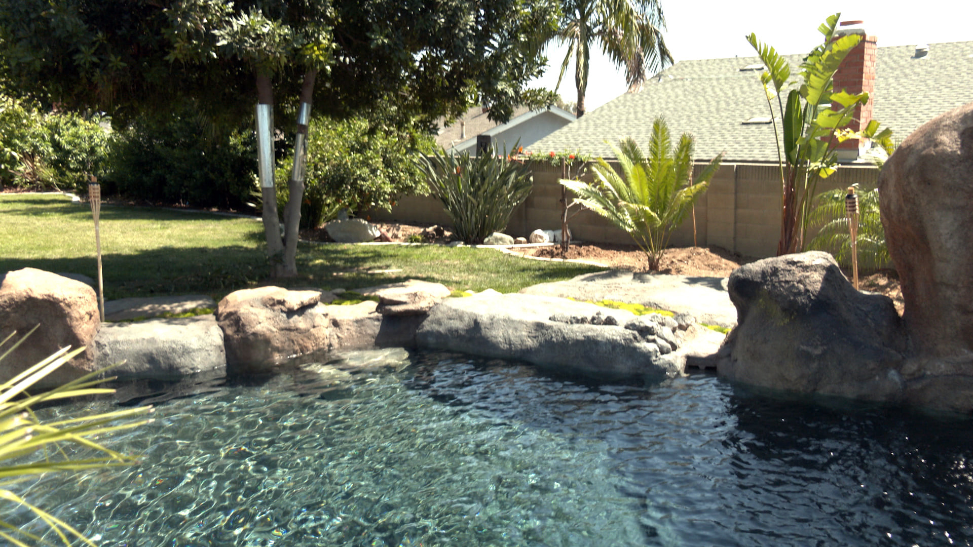 Backyard pond and rock water feature with scattered concrete boulders