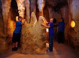 Children exploring indoor cave attraction with stalagmite formations