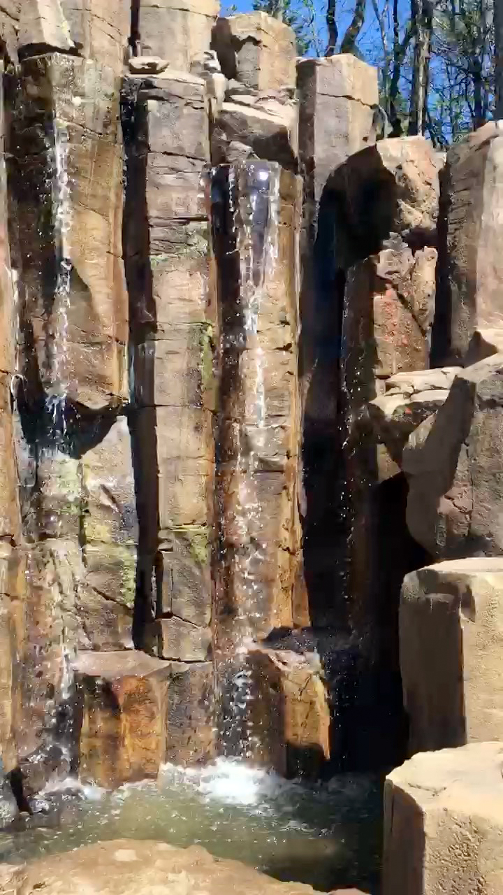 Concrete rock canyon feature with vertical columns and waterfall streams