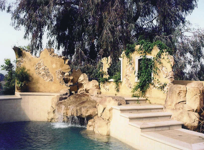 Backyard pool with golden-toned concrete rock walls