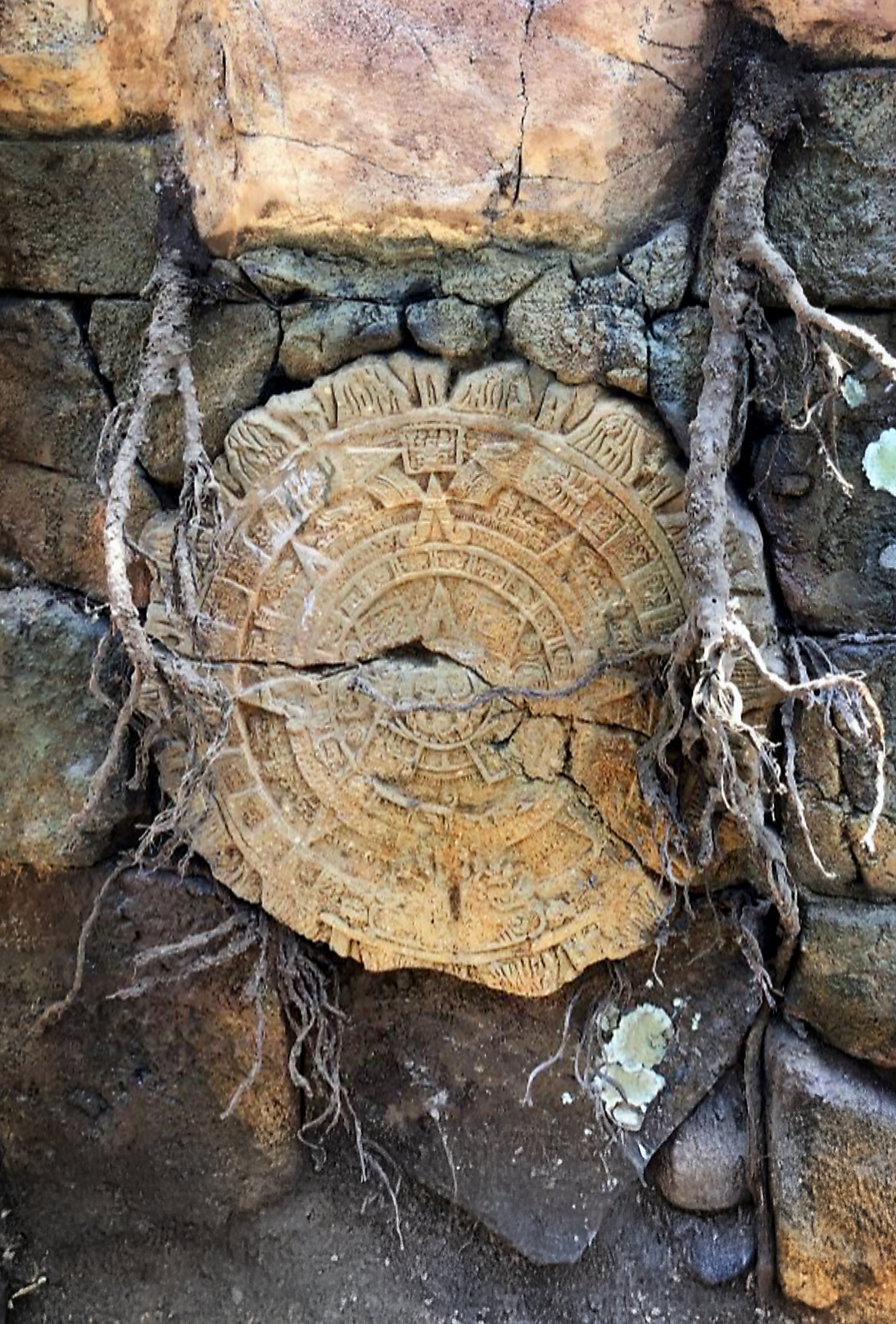 realistic artificial rock and stone wall with embedded mayan calendar carved into a circular piece of stone.